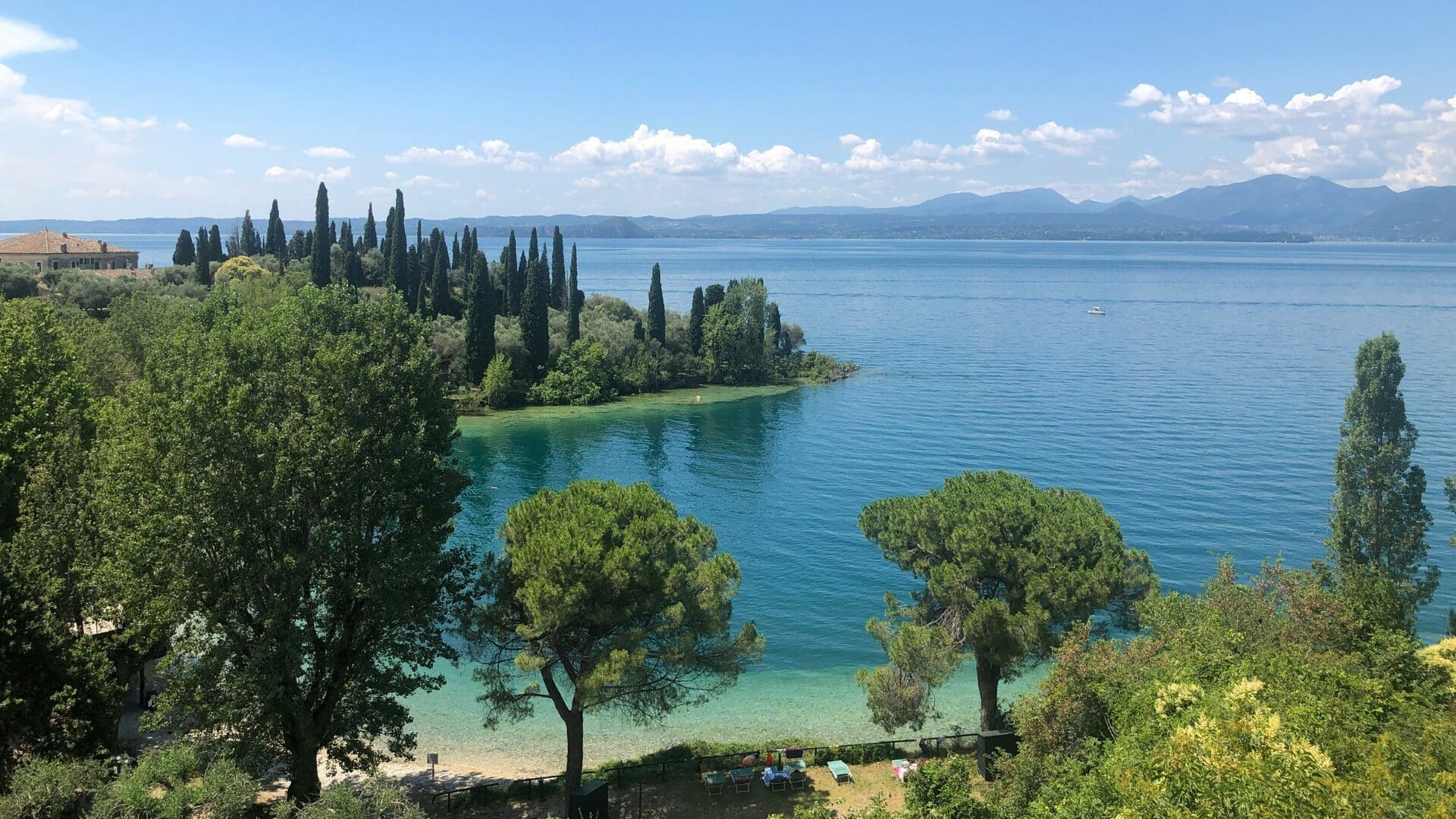 Lake Garda lake holiday with clear blue water, cypress trees and scenic Italian shoreline views